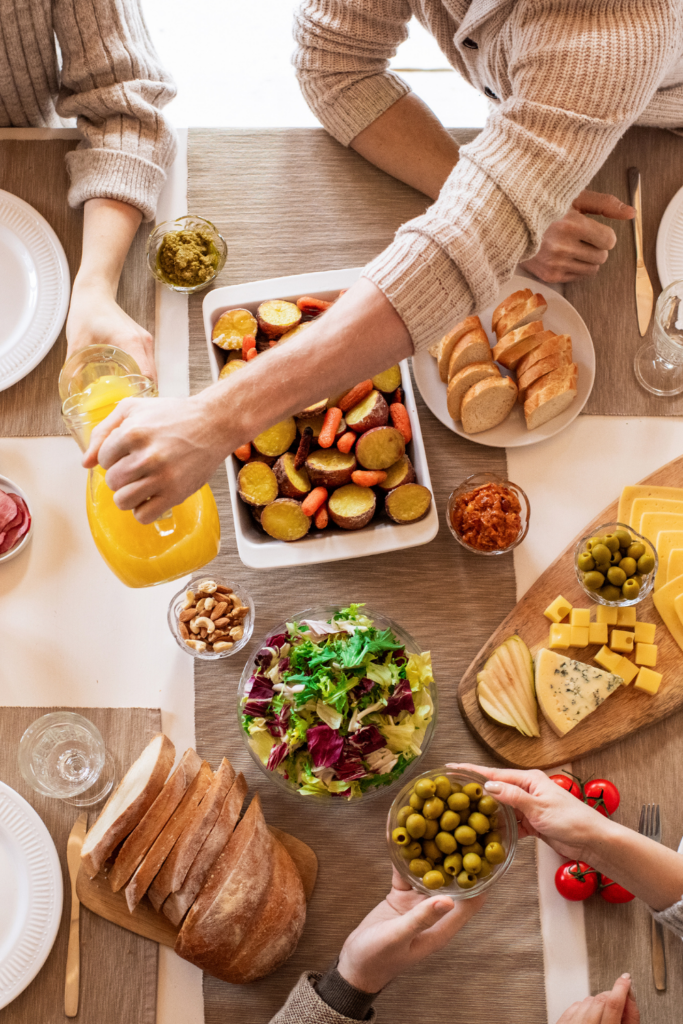 Draufsicht auf gedeckten Tisch mit vielen Speisen, Hände greifen zu – Essen im Urlaub am Buffet